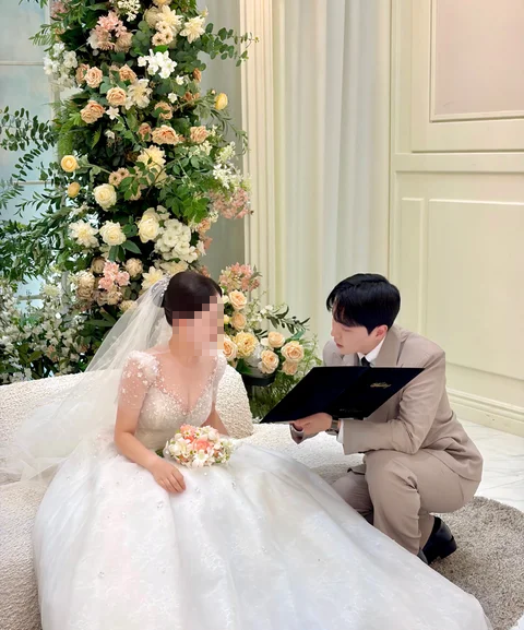 베이지색 정장을 입고 신부님과 자료를 확인하는 김민울 사회자